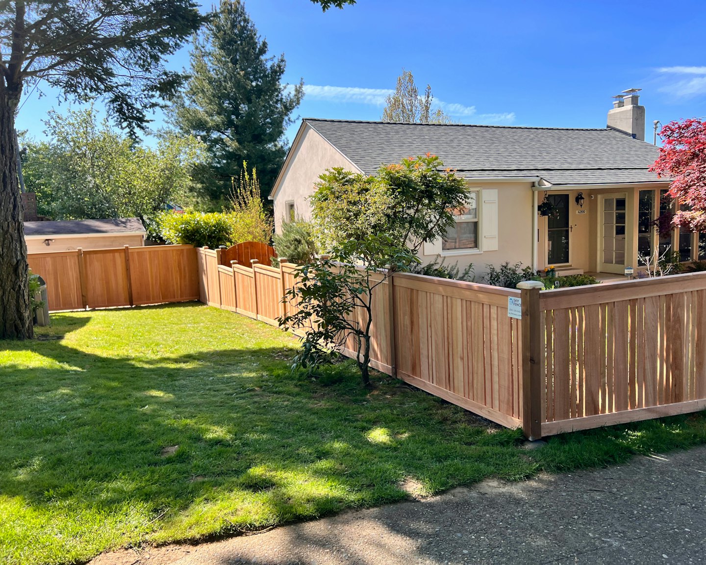 A single-story house with a wooden fence and green lawn.